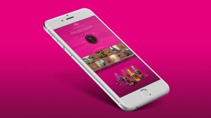billede af iPhone med screenshot af Anthon Berg Spin the bottle app på lyserød baggrund
