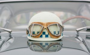hvid racerhjelm med retro racer briller ovenpå motorhjelmen af ældre bil
